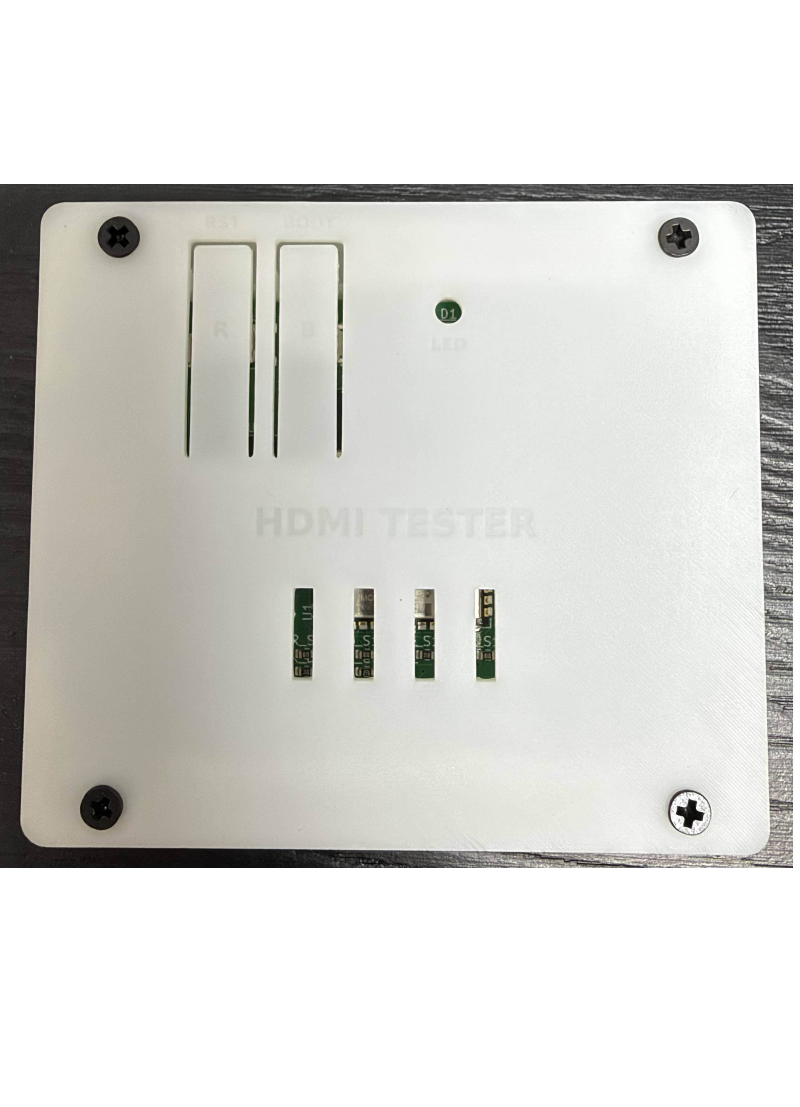 HDMI tester in its assembled white protective housing with four corner screws and indicator openings